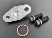 An image showing a silver oil feed flange with an integrated -4 AN port, accompanied by an orange O-ring and two black M8X1.25 bolts on a dark background.