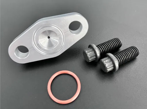 An image showing a silver oil feed flange with an integrated -4 AN port, accompanied by an orange O-ring and two black M8X1.25 bolts on a dark background.