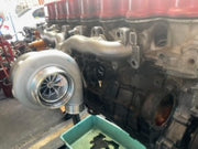 A Ford SOHC Turbo Manifold Kit installed on an engine, featuring a silver manifold and adapter plate.